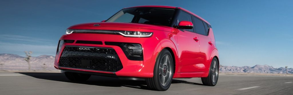 One red color 2021 Kia Soul is running on the road.