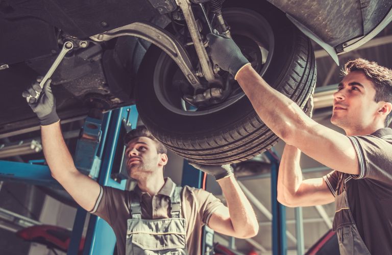 Two technicians servicing a vehicle